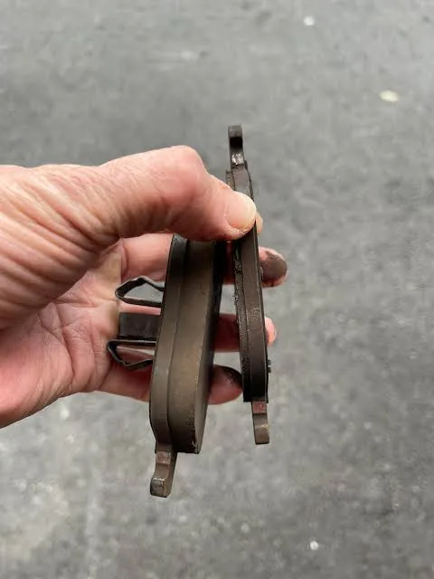 Inner and outer Mercedes-Benz brake pads held side by side showing uneven wear