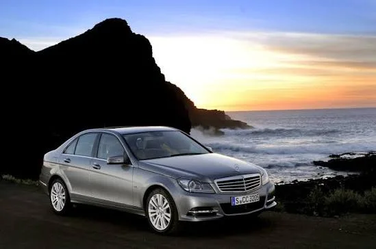 Silver 2007–2014 Mercedes-Benz C-Class sedan parked by the ocean at sunset