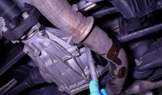 Technician working on a Mercedes-Benz rear differential under the car