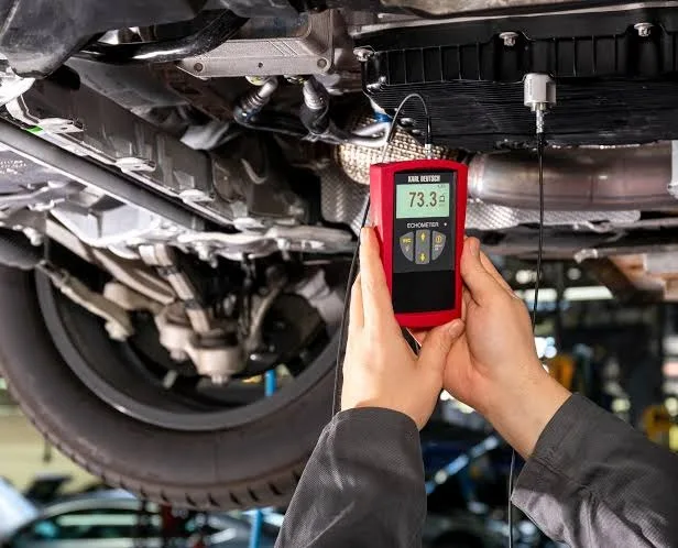 Technician setting the fluid level of a Mercedes-Benz 725 transmission with an ultrasonic sensor under the car